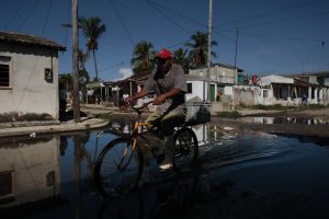 Un ciclista transita por una calle inundada en la localidad de Batabanó, en el sur de la provincia cubana de Mayabeque. La zona se caracteriza por la presencia de zonas costeras bajas y, a menudo cenagosas, proclive a frecuentes inundaciones durante el paso de huracanes e intensas lluvias. Foto: Jorge Luis Baños/IPS