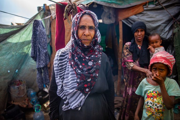 Una mujer yemení desplazada fuera de unas tiendas precarias, que comparte con su familia, en un campamento improvisado. Foto: OIM