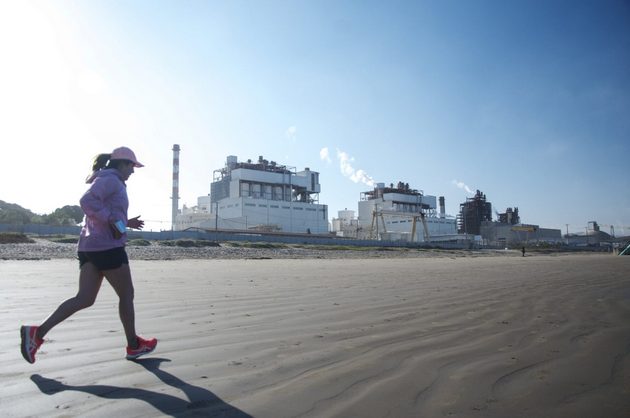 Residentes de Quintero y Puchuncaví hacen ejercicio en la playa, con el parque industrial de fondo. Foto: Saúl Mancilla