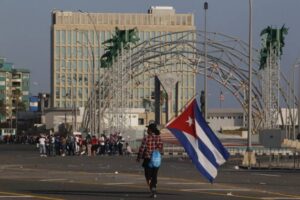 Una mujer porta una bandera de Cuba ante la sede de la embajada de Estados Unidos en La Habana, durante un acto en apoyo a la revolución. La Casa Blanca estudia aumentar el personal en su delegación, que quedó prácticamente vacía tras el cierre de los servicios consulares en 2017. Foto: Jorge Luis Baños / IPS